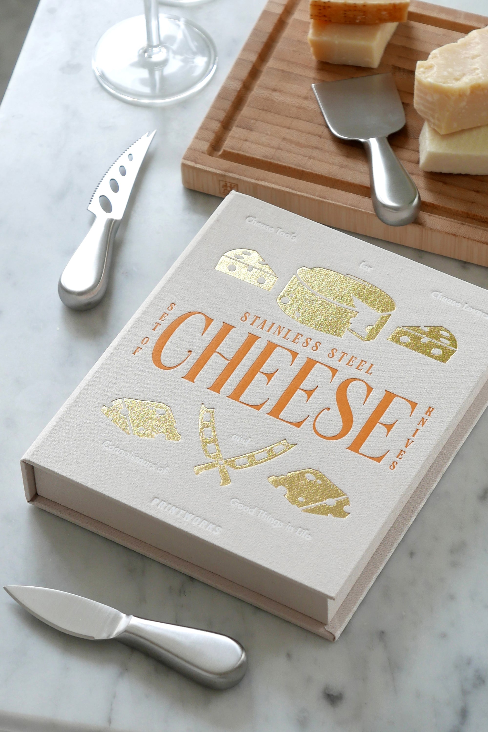 Cheese book with cheese and tools on a marble surface
